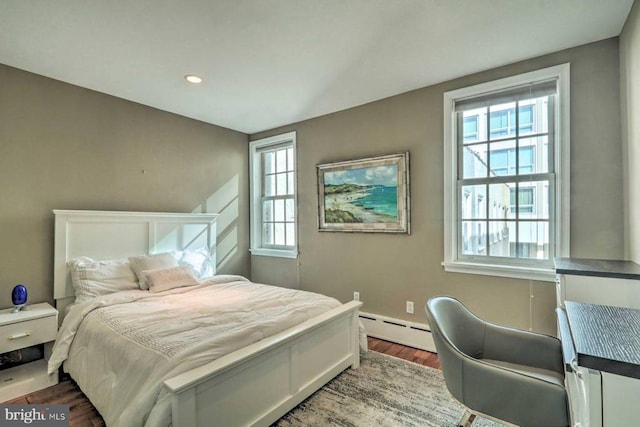 bedroom with a baseboard heating unit and hardwood / wood-style flooring