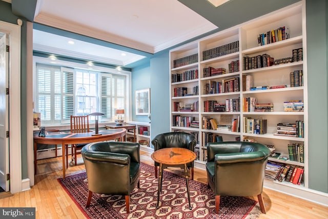 sitting room featuring a tray ceiling, ornamental molding, built in shelves, and light hardwood / wood-style flooring