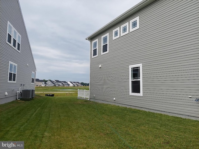 view of property exterior with central AC and a yard