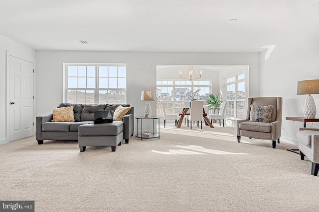 carpeted living room featuring plenty of natural light and a chandelier