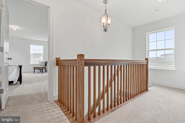 hall featuring an inviting chandelier and light carpet