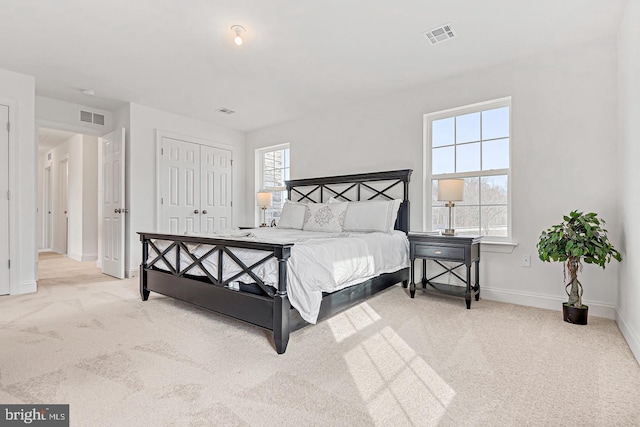 bedroom featuring a closet, light carpet, and multiple windows