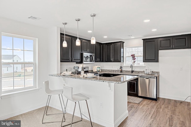 kitchen with stainless steel appliances, light stone countertops, and a wealth of natural light