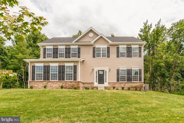 colonial home featuring a front yard and central air condition unit