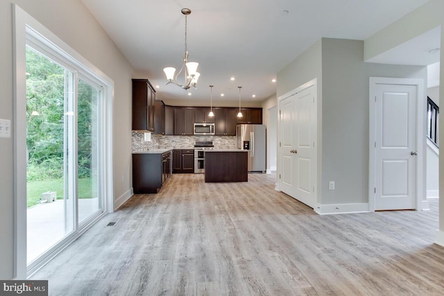 kitchen with a chandelier, pendant lighting, tasteful backsplash, dark brown cabinets, and appliances with stainless steel finishes