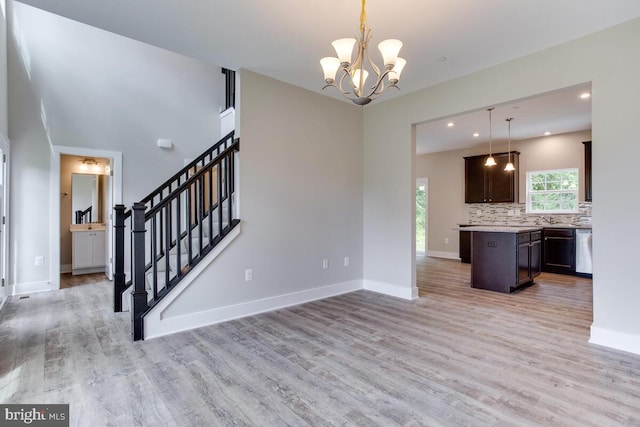 kitchen with pendant lighting, a notable chandelier, backsplash, dark brown cabinetry, and light wood-type flooring