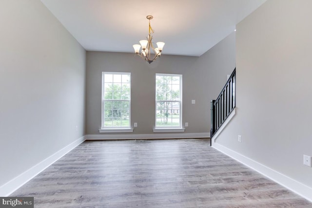 empty room featuring light hardwood / wood-style floors and a notable chandelier