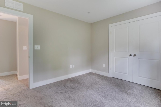 unfurnished bedroom with a closet and light carpet