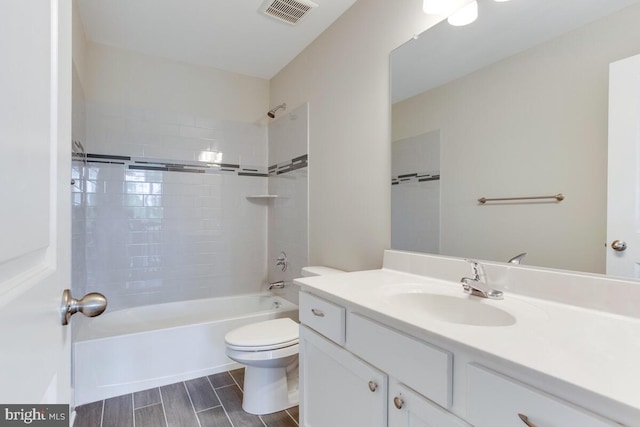 full bathroom with toilet, large vanity, and tiled shower / bath combo