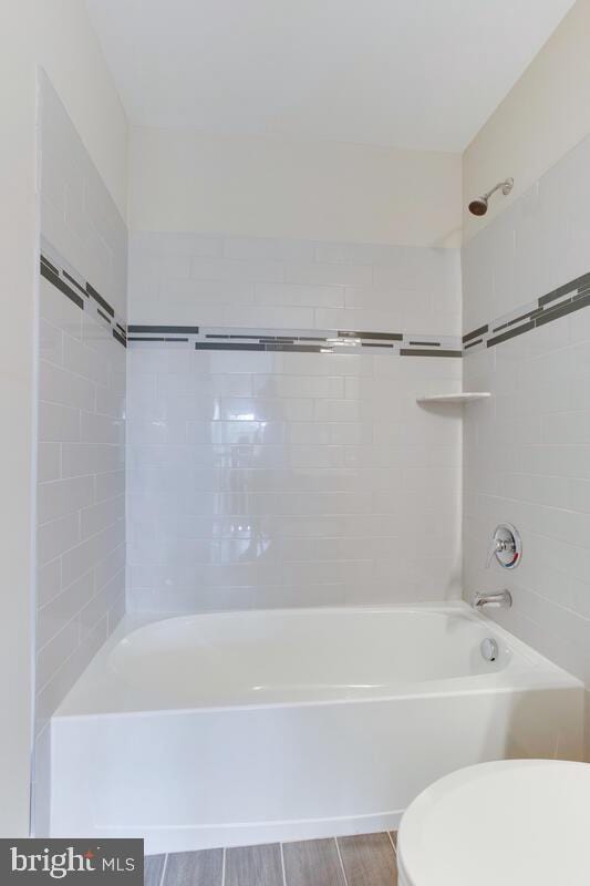 bathroom featuring hardwood / wood-style floors, toilet, and tiled shower / bath