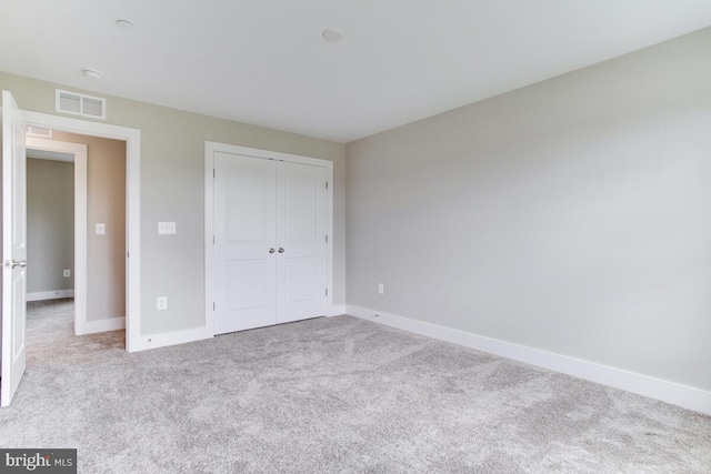 unfurnished bedroom featuring light colored carpet and a closet