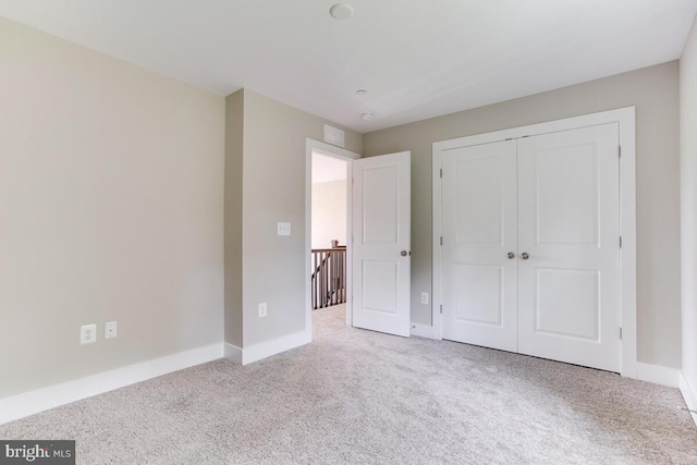 unfurnished bedroom with light carpet and a closet