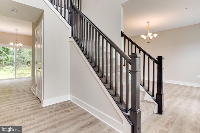 staircase featuring an inviting chandelier and light wood-type flooring