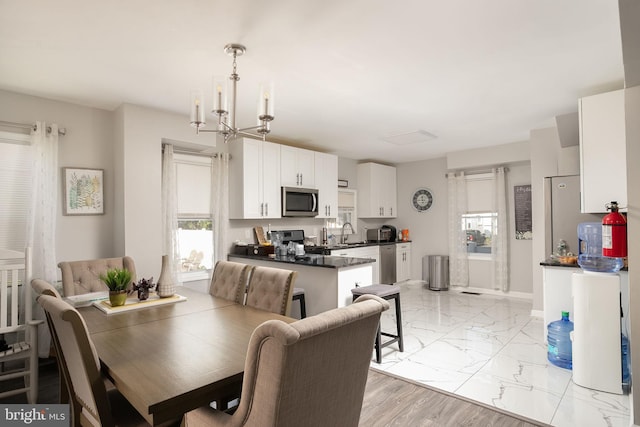 dining area featuring an inviting chandelier, sink, and light wood-type flooring