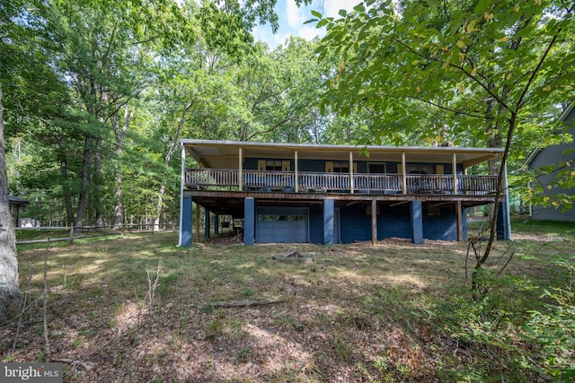 rear view of house with a deck, a garage, and a yard