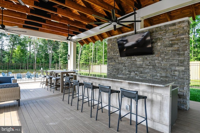 deck with a bar, a swimming pool, and ceiling fan