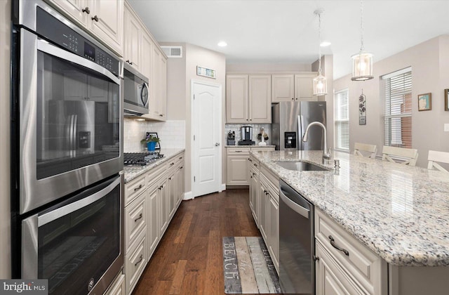 kitchen featuring appliances with stainless steel finishes, tasteful backsplash, decorative light fixtures, dark hardwood / wood-style flooring, and sink