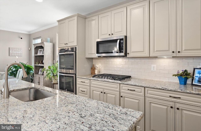 kitchen with appliances with stainless steel finishes, tasteful backsplash, light stone countertops, ornamental molding, and sink