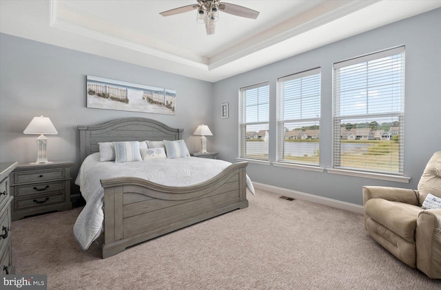 carpeted bedroom featuring a raised ceiling and ceiling fan