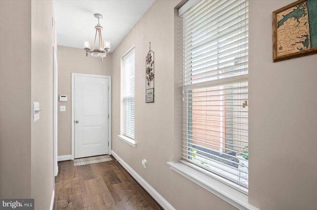 doorway to outside featuring a notable chandelier and dark hardwood / wood-style flooring