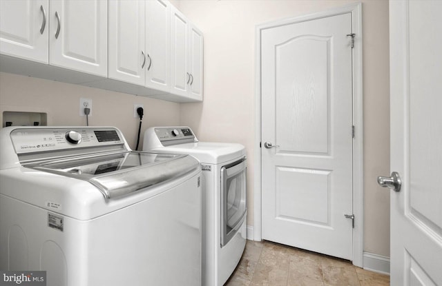 laundry area with light tile flooring, separate washer and dryer, and cabinets