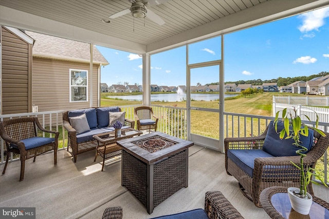 sunroom / solarium with ceiling fan and a water view