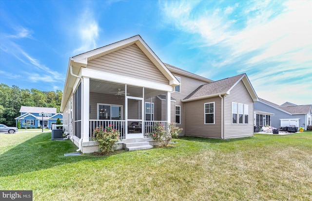 rear view of property with central AC unit, a sunroom, and a lawn