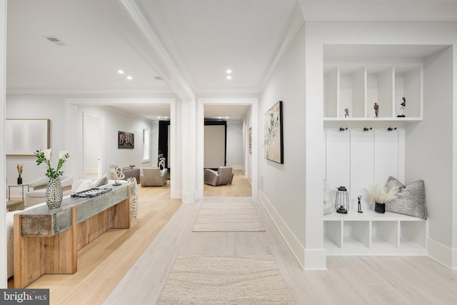 mudroom with built in shelves, light wood-type flooring, and crown molding