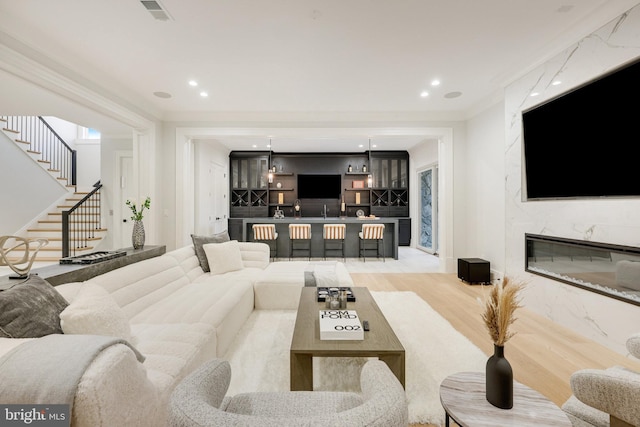 living room with hardwood / wood-style flooring, crown molding, a fireplace, and bar