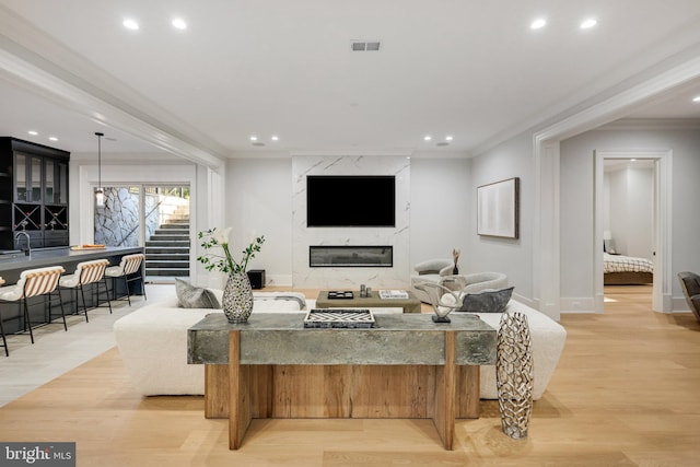 living room featuring a fireplace, light wood-type flooring, and ornamental molding