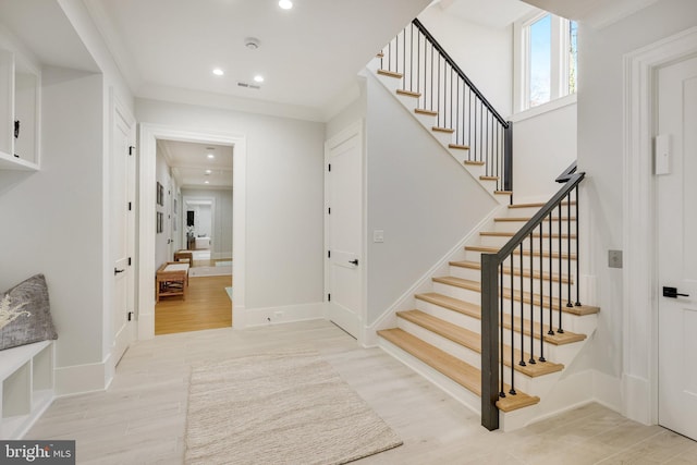 stairs with wood-type flooring and ornamental molding