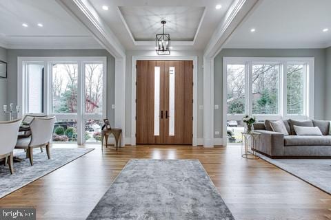 entryway featuring a tray ceiling, light hardwood / wood-style flooring, and a chandelier