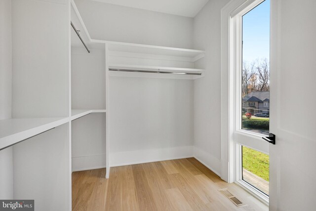 walk in closet with light hardwood / wood-style floors