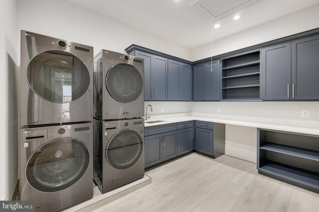 laundry room featuring sink, cabinets, washing machine and dryer, light hardwood / wood-style flooring, and stacked washer and clothes dryer