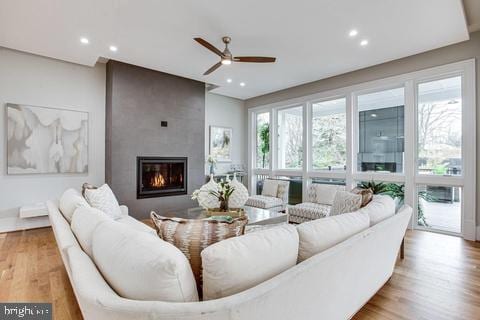 living room with ceiling fan, a fireplace, light hardwood / wood-style floors, and plenty of natural light