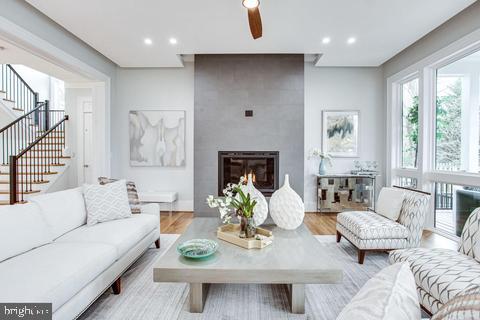 living room featuring ceiling fan, light wood-type flooring, and a fireplace