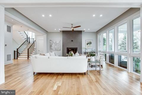 living room with ceiling fan, a large fireplace, and light wood-type flooring