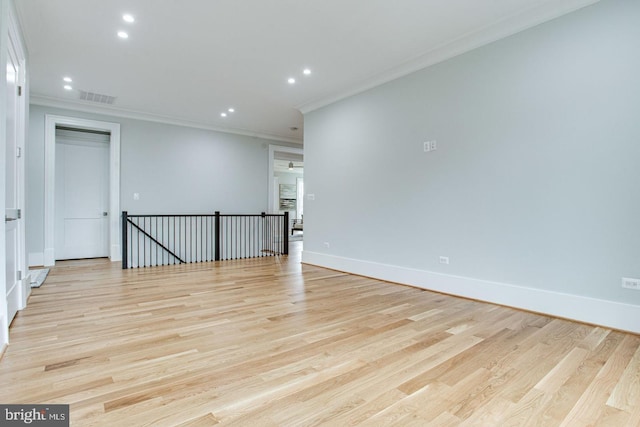 empty room featuring light wood-type flooring and ornamental molding