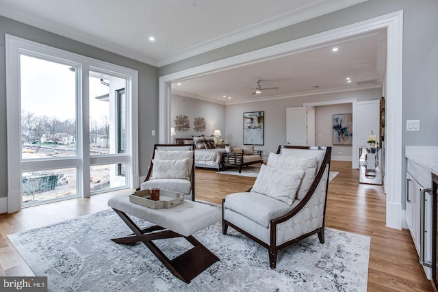 living room with ceiling fan, light hardwood / wood-style floors, a healthy amount of sunlight, and crown molding