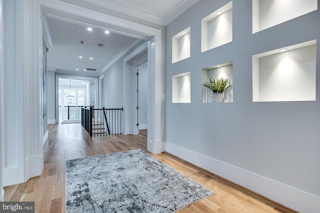 hallway with light wood-type flooring and ornamental molding