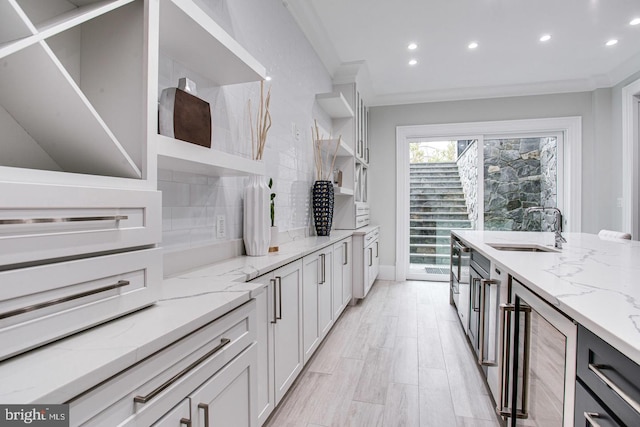 kitchen with light stone countertops, backsplash, crown molding, sink, and wine cooler