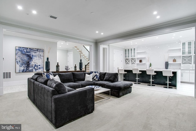 carpeted living room with bar and crown molding