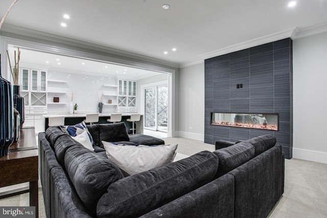 living room with a tile fireplace, light colored carpet, and crown molding