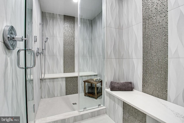 bathroom with a shower with door and tile walls