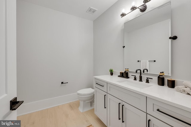 bathroom featuring vanity, wood-type flooring, and toilet