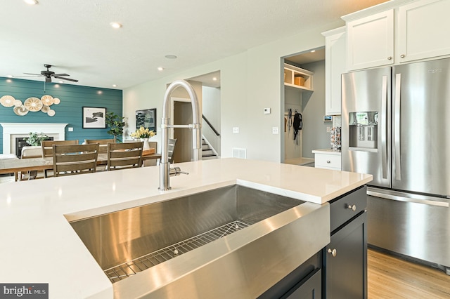 kitchen featuring white cabinetry, sink, light hardwood / wood-style flooring, ceiling fan, and stainless steel refrigerator with ice dispenser