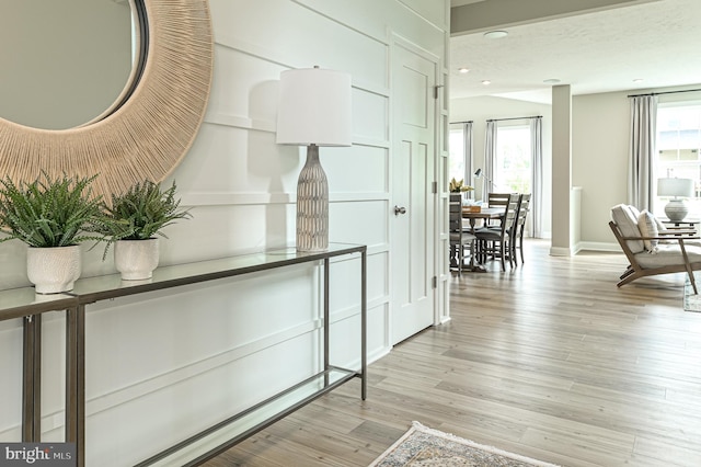 corridor with a wealth of natural light and light hardwood / wood-style flooring