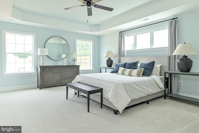 carpeted bedroom featuring a tray ceiling and ceiling fan