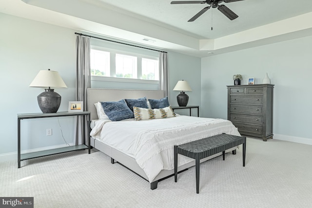 bedroom featuring light colored carpet, a tray ceiling, and ceiling fan