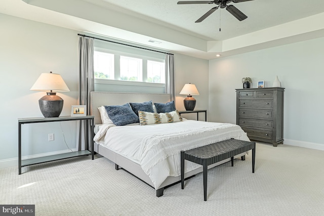 carpeted bedroom featuring a tray ceiling and ceiling fan